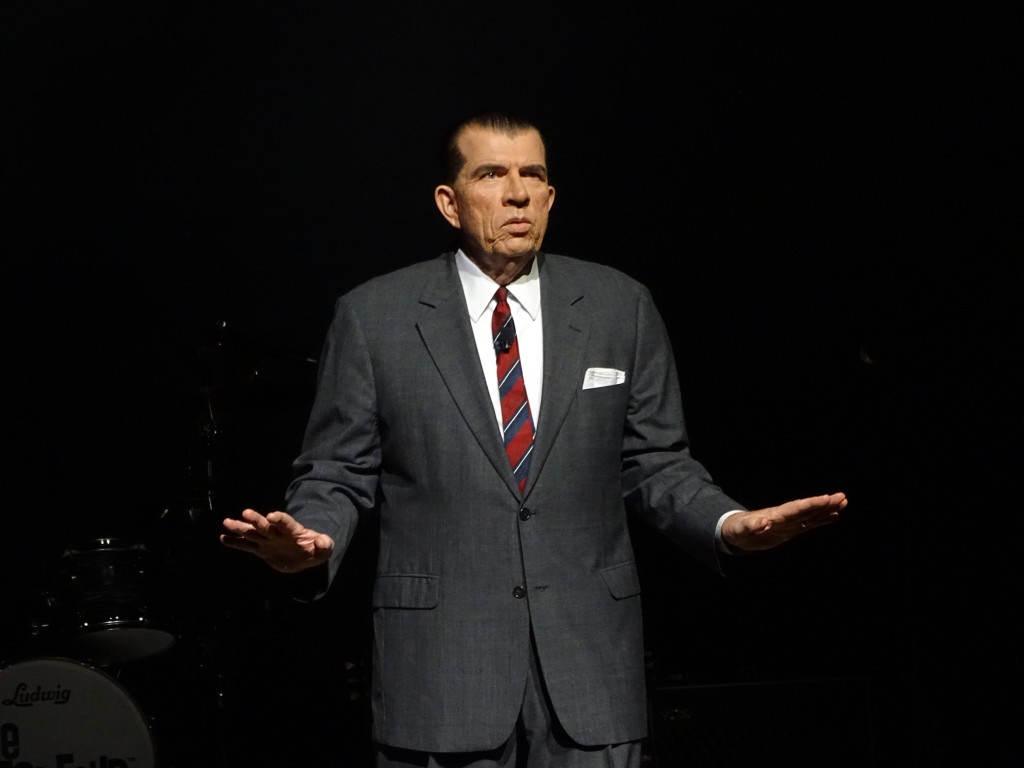 "Ed Sullivan," played by George Trullinger, introduces the band.